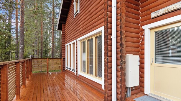 A wooden cabin with a deck, large windows, and a door with a window. - Kevätruska a by Interhome (Kittilä)