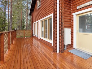 A wooden cabin with a deck, large windows, and a door with a window.