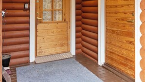 A wooden log cabin entrance with a glass door and a wooden door. - Kevätruska a by Interhome (Kittilä)