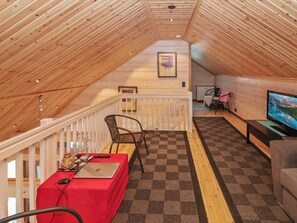 A cozy room with a wooden ceiling, a red table with a laptop, a chair, and a TV on the wall. - Huvila tornionjoen rannalla by Interhome (Pello)