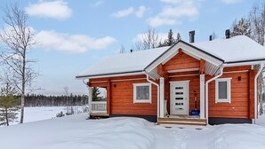 Una casa de madera con techo nevado y un porche delantero.