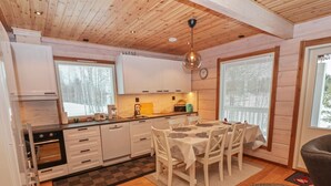 Una cocina moderna con armarios blancos, una mesa de comedor con sillas y un techo de madera.