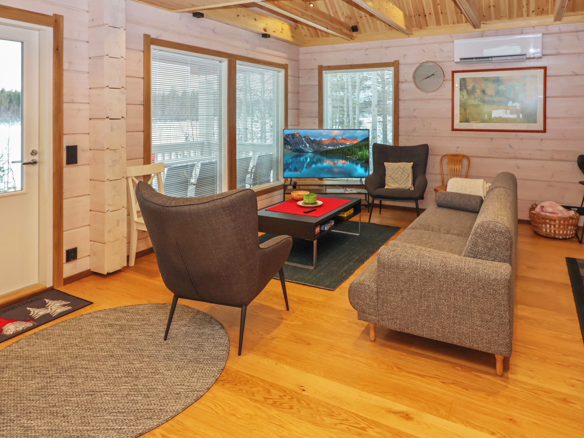 Una sala de estar acogedora con televisor, sofá, sillón y piso de madera.