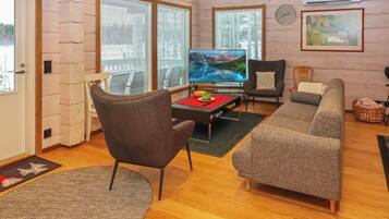 Una sala de estar acogedora con televisor, sofá, sillón y piso de madera.