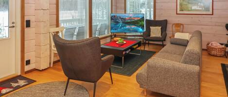 A cozy living room with a television, sofa, armchair, and a wooden floor.
