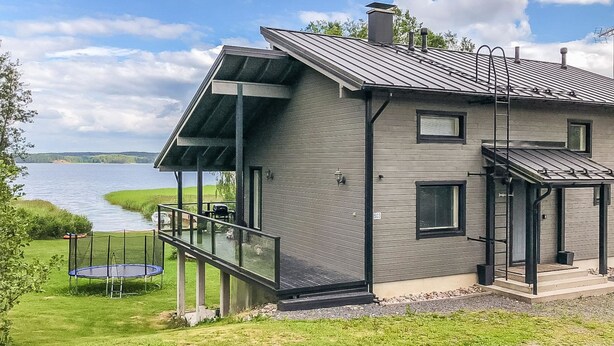 Una casa moderna con una amplia terraza con vistas a un lago, un porche cubierto y el número 503 a la vista.
