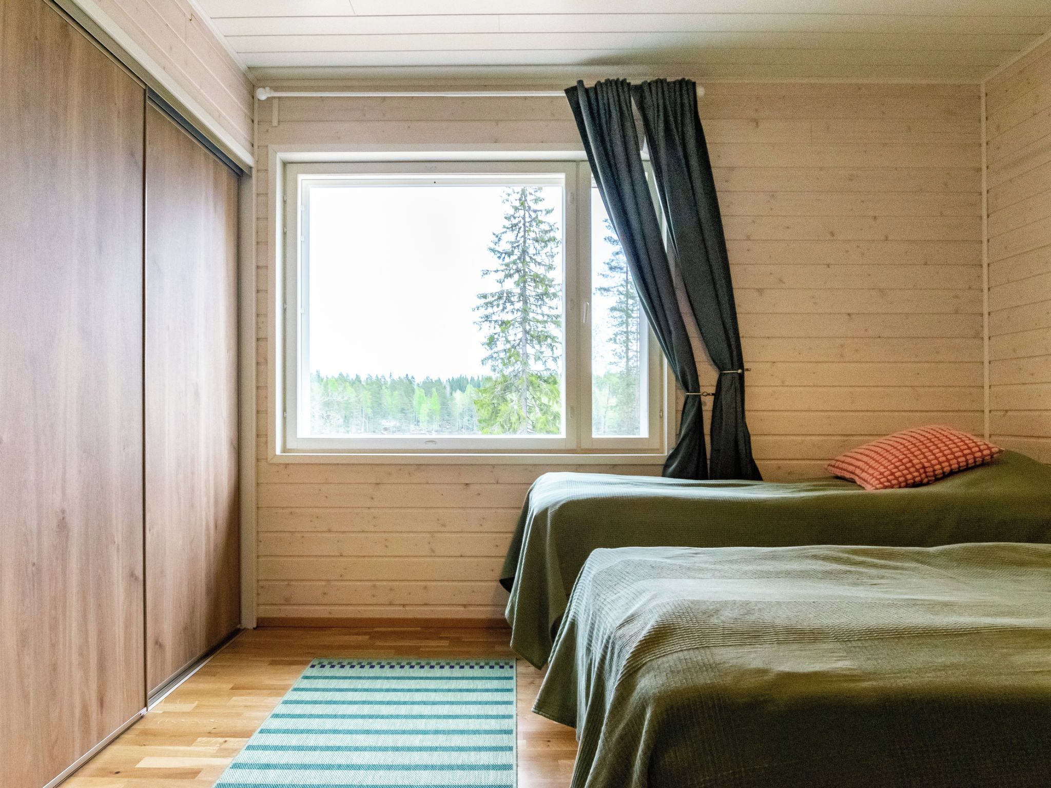 Une chambre avec deux lits, une fenêtre et une vue sur les arbres.