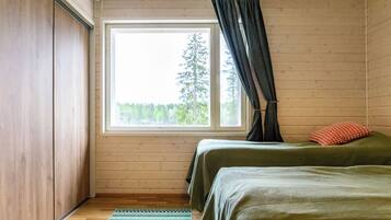 Une chambre avec deux lits, une fenêtre et une vue sur les arbres.
