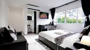 Camera d'hotel moderna con un letto grande, una scrivania, una TV e vista sulla città.
