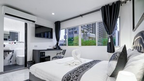 Una camera d'albergo moderna con un letto grande, una scrivania, una TV a schermo piatto e vista sulla città.