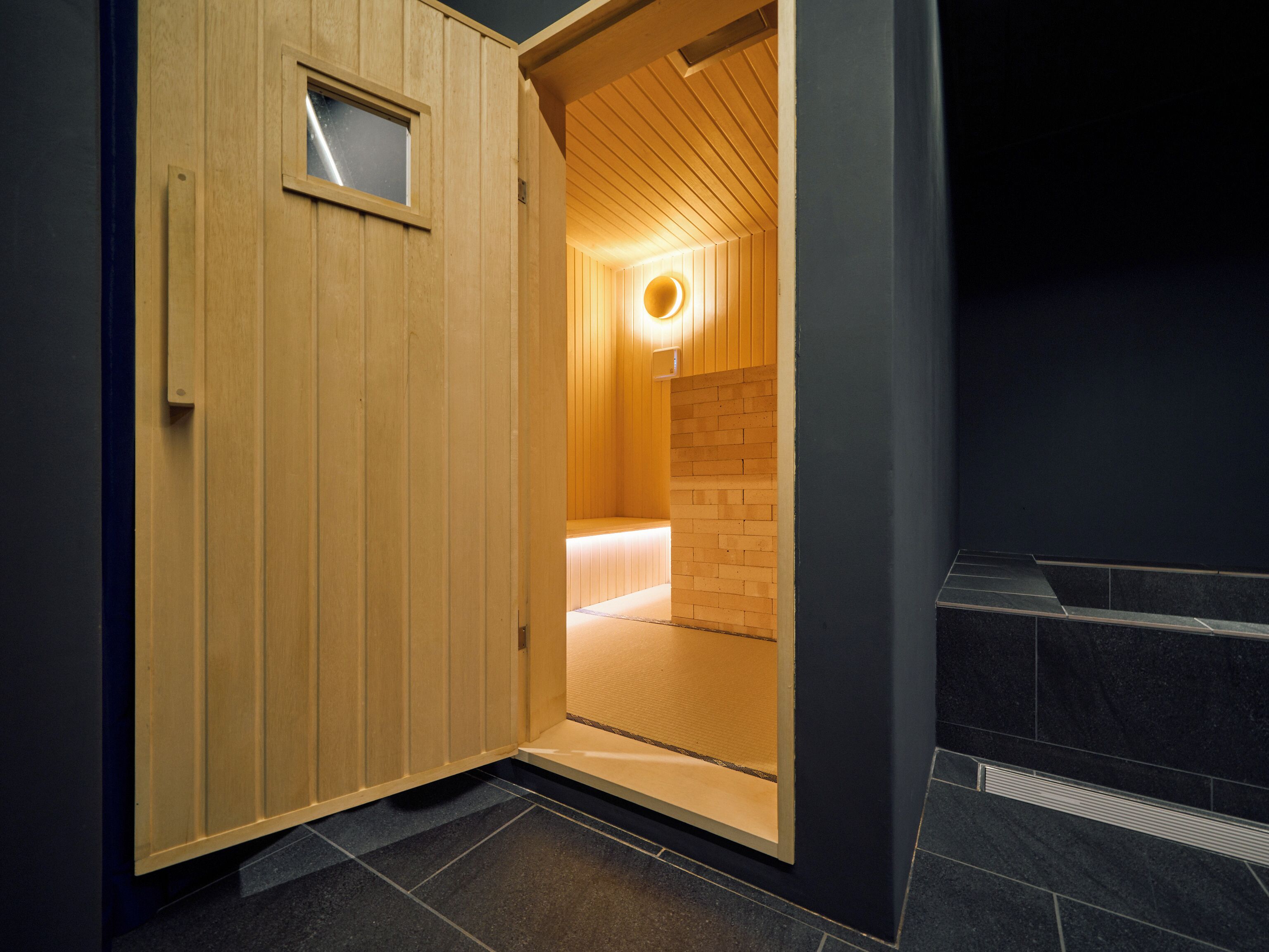 Uma sala de sauna com paredes de madeira e uma pequena janela.