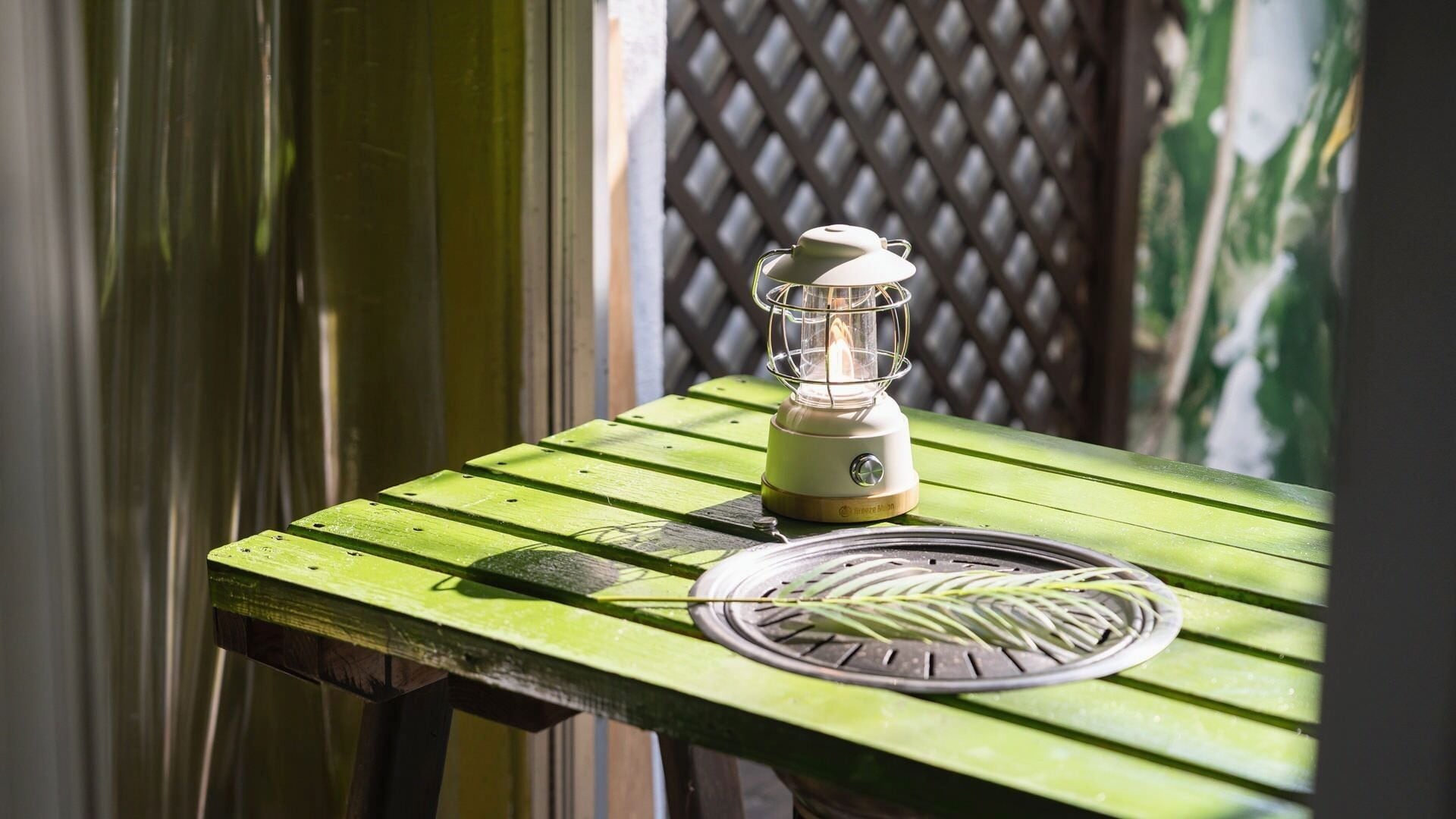 A green wooden table with a portable lantern and a coiled wire.