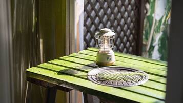 A green wooden table with a portable lantern and a coiled wire.
