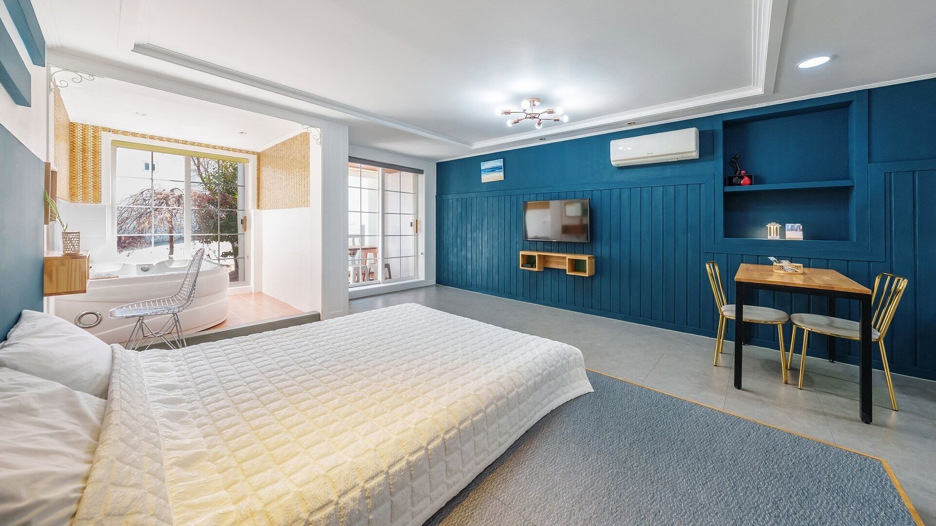 A bedroom with a bed, a desk, and a chair. There is a window and a door.
