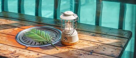 Une table en bois, un petit radiateur mobile, une feuille et un barbecue.