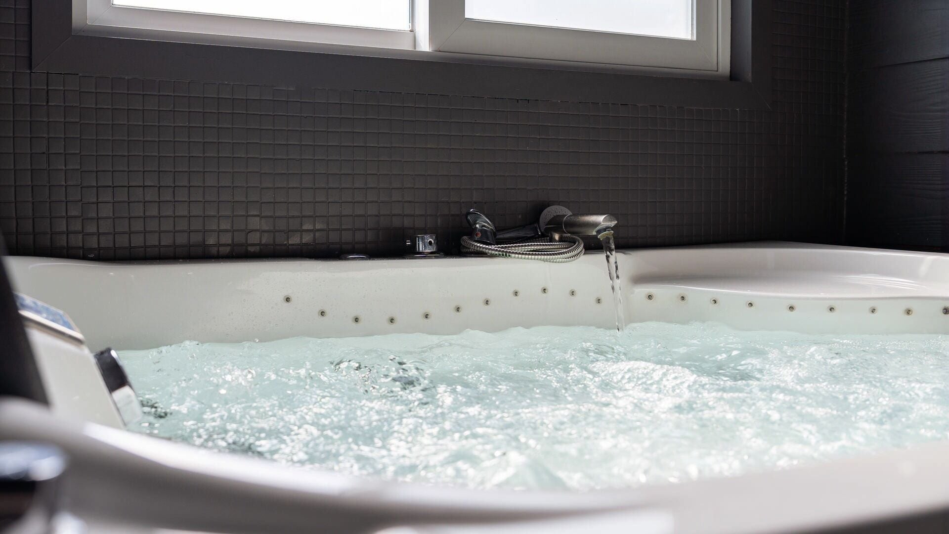 A hot tub with water jets, a faucet, and a control panel.