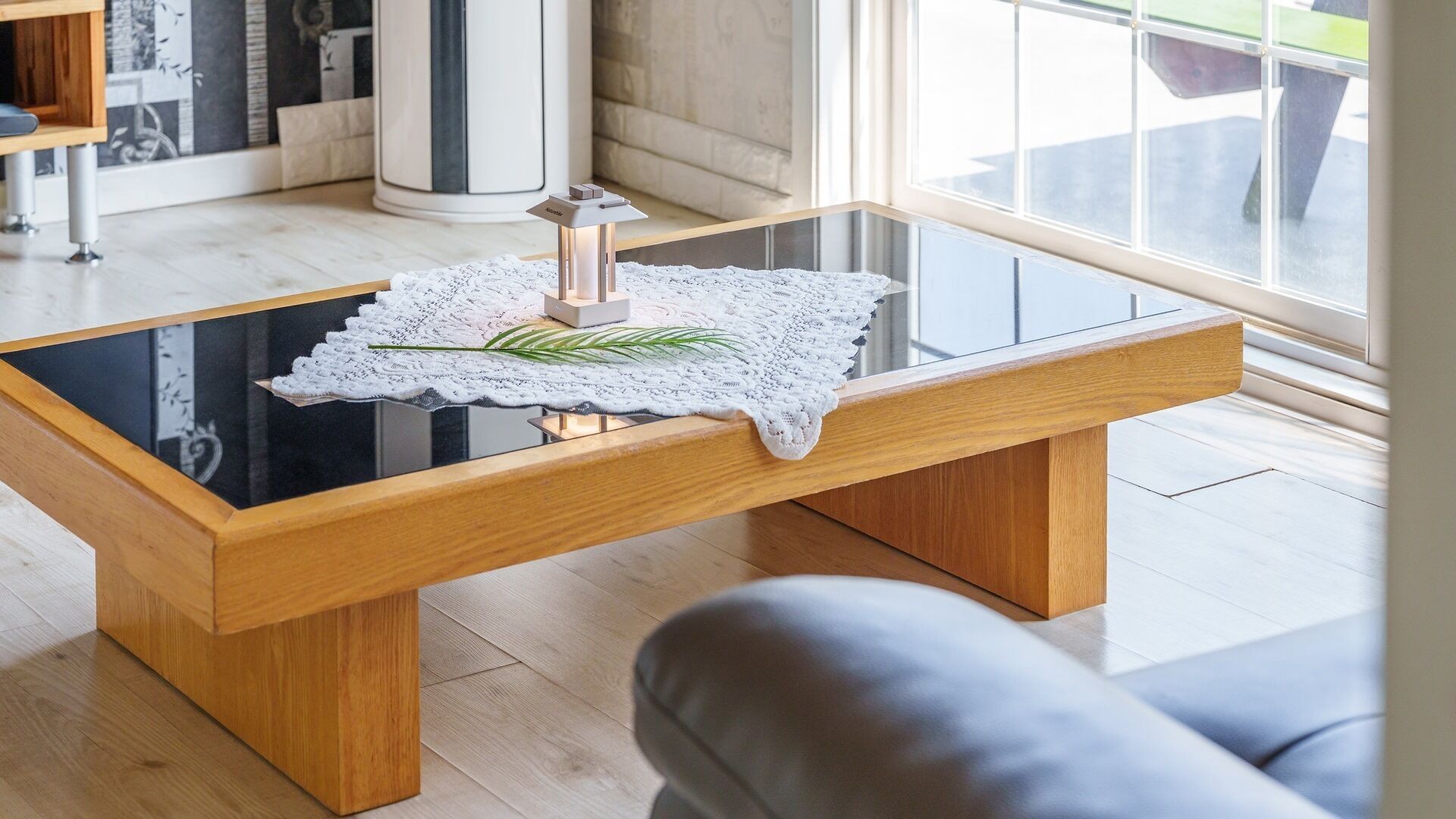 Una sala moderna con una mesa de centro de cristal, un banco de madera y un objeto decorativo sobre la mesa.