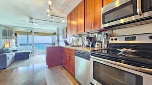 A modern kitchen with stainless steel appliances, wooden cabinets, and a large island.