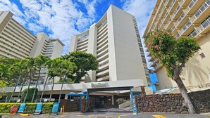 A modern hotel entrance with a stone facade, a covered entrance, and a clear blue sky.