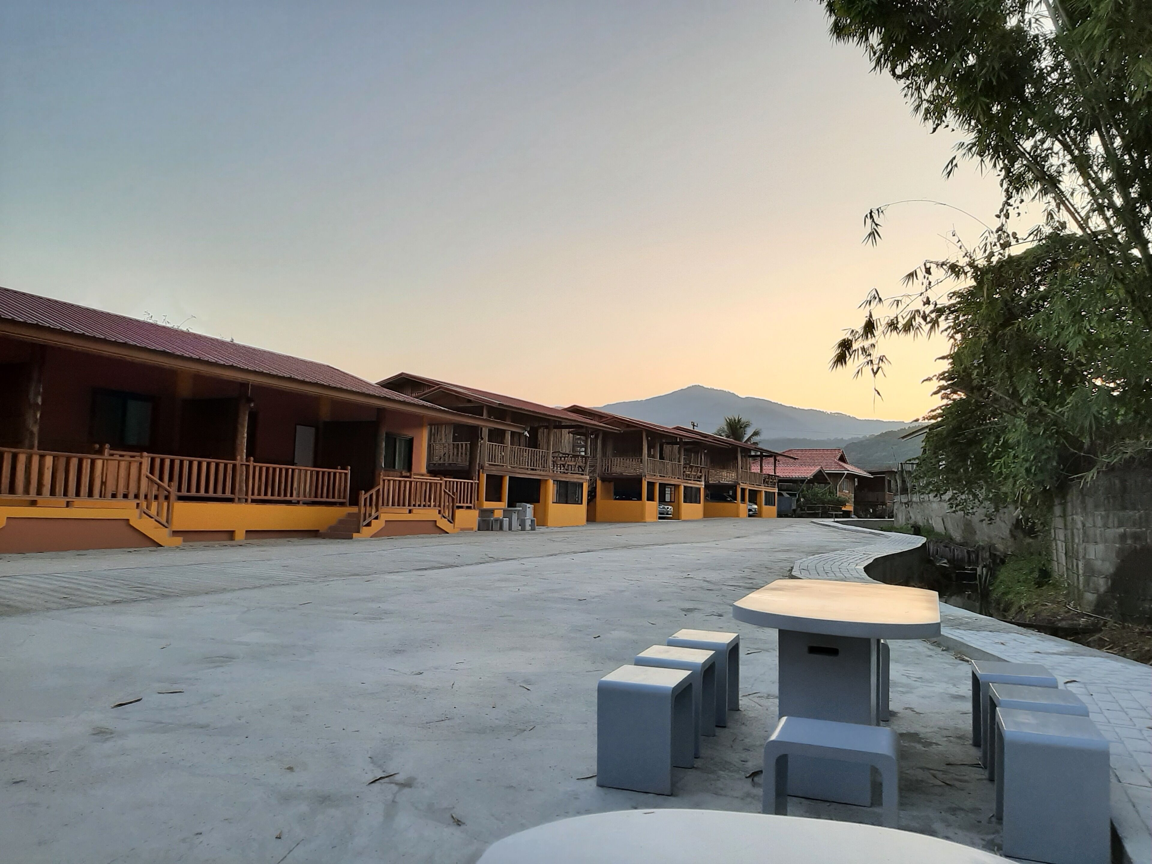 A hotel with multiple balconies, a courtyard, and a view of mountains.