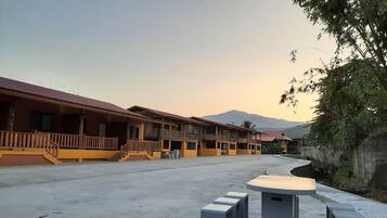 A hotel with multiple balconies, a courtyard, and a view of mountains.