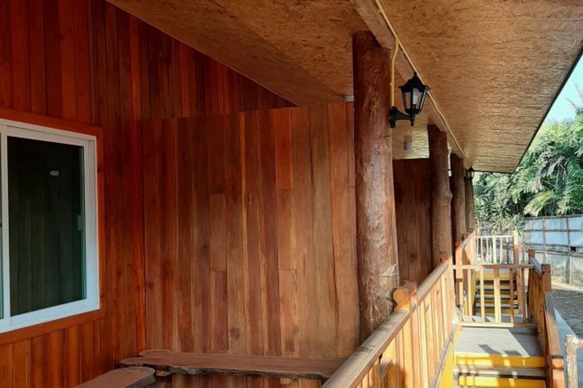 A wooden cabin with a porch, a window, and a staircase leading outside.