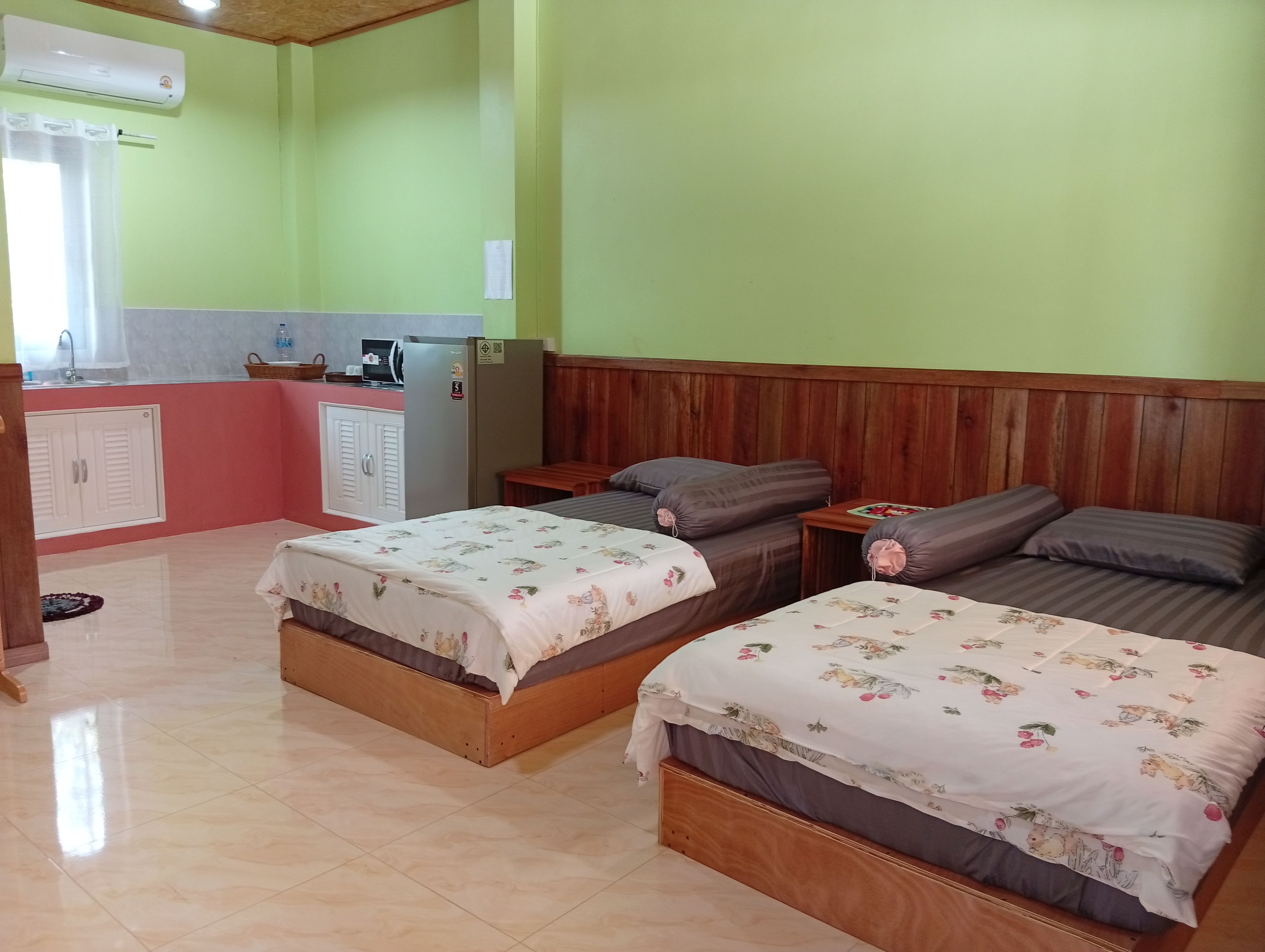 Ein Zimmer mit zwei Betten, einer Küchenzeile und einem hölzernen Kopfstück.