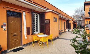 Ein Gebäude mit einer geschlossenen Holztür, einem Fenster mit Gitterwerk und einem kleinen Balkon mit Tisch und Stühlen.