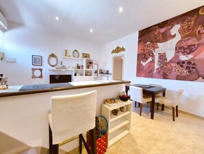 Eine moderne Küche mit Kochinsel, weißen Schränken und einem Essbereich mit Stühlen und Tisch.