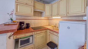 A compact kitchen with light-colored cabinets, a microwave, a coffee maker, and a refrigerator. - Studio cabine 4 personnes,copropriété avec  Piscine (LE LAVANDOU)