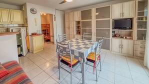 A compact kitchen with a dining area, a ceiling fan, and a TV on a cabinet. - Studio cabine 4 personnes,copropriété avec  Piscine (LE LAVANDOU)