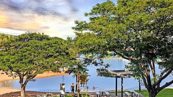 Un cadre paisible au bord du lac, avec une terrasse en bois, des tables de pique-nique et un petit pont enjambant l’eau.