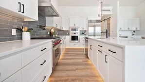 Una cocina moderna con armarios blancos, electrodomésticos de acero inoxidable y suelo de madera.