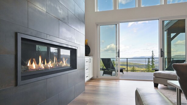 Una sala de estar moderna con chimenea, un balcón con vistas y un amplio ventanal corredero.