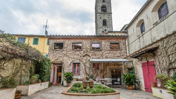 A courtyard with a central fountain, stone walls, and a tower in the background. - GuestHost - San Rocco Apartment Borgo a Mozzano - Lucca (Borgo a Mozzano)
