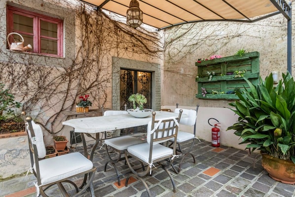Une terrasse avec une table et des chaises, un extincteur et des plantes en pot.