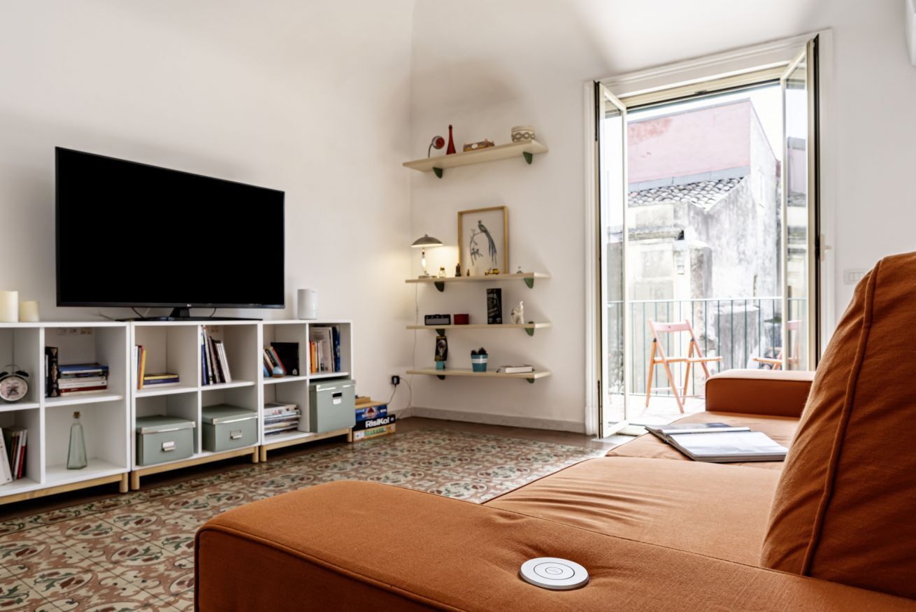 A living room with a flat-screen TV, bookshelves, a sofa, and a window with a view.