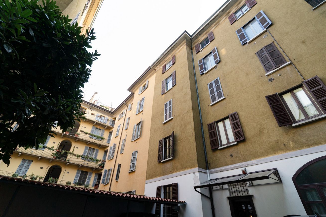 Un immeuble à plusieurs étages, doté de balcons, d’un toit recouvert de tuiles et d’une entrée située à l’angle.