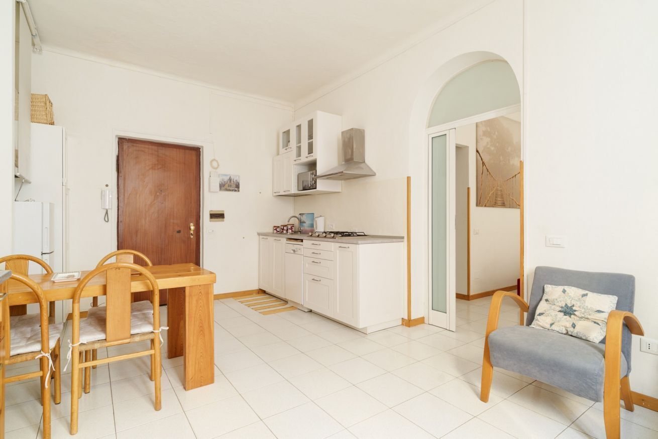 A compact kitchen with white cabinets, a wooden dining table, and chairs.