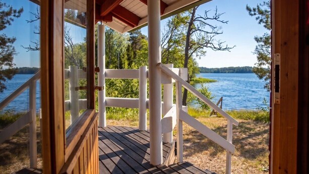 Una terraza de madera con barandilla blanca que da a un lago.