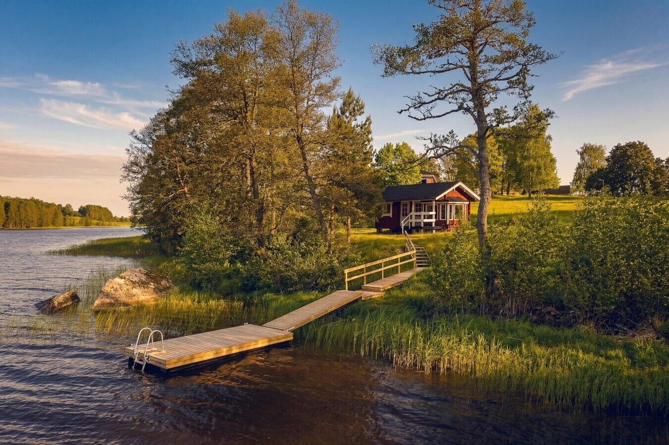 Eine Holzhütte am Seeufer mit einem Steg, der zum Haus führt.