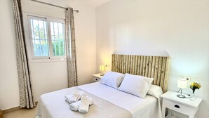 Habitación de hotel con una cama grande, dos mesitas de noche, una ventana con cortinas y vistas a zonas verdes.