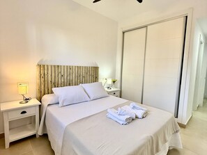 A hotel room with a bed, a nightstand, a lamp, and a wardrobe.