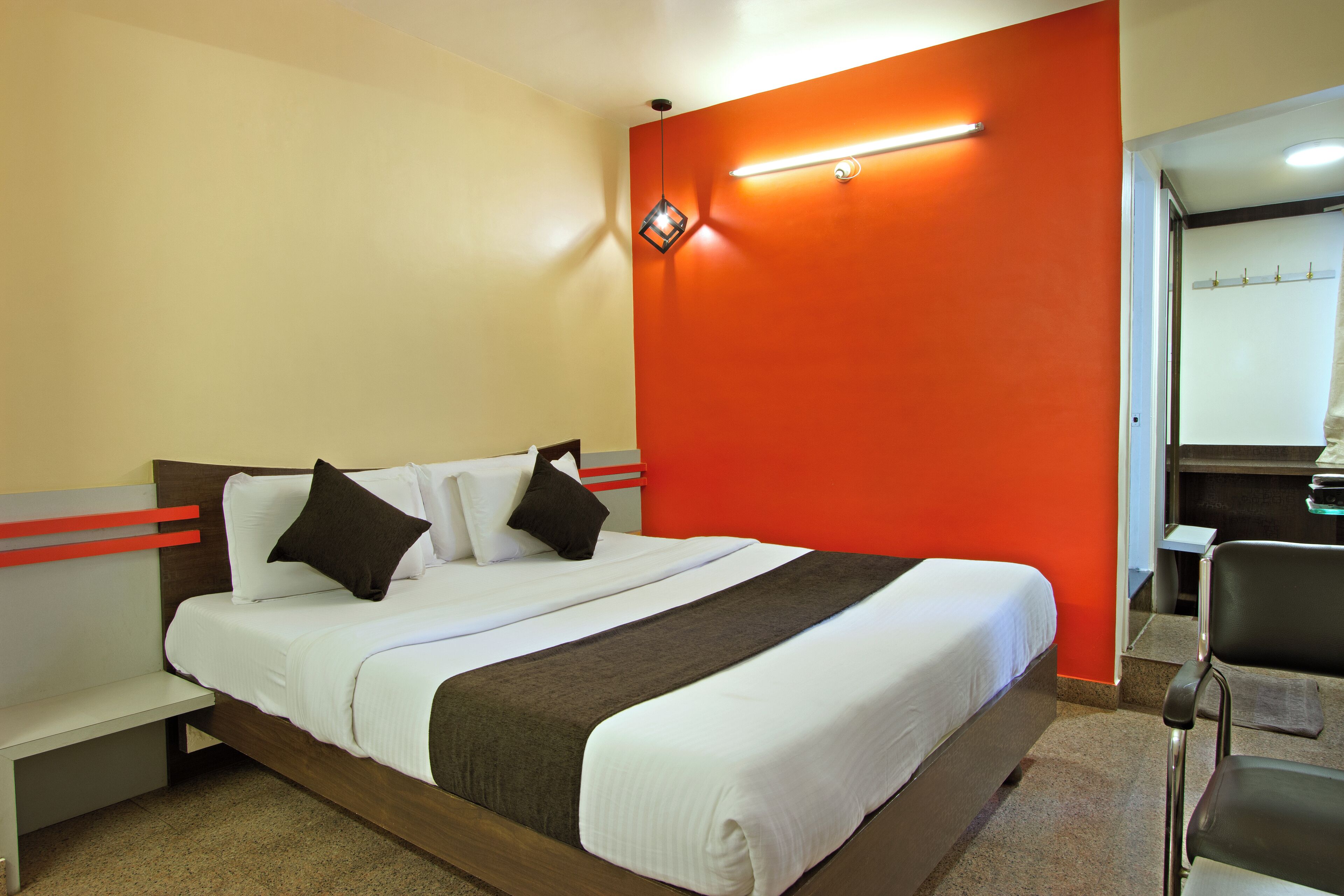 A hotel room with a bed, a nightstand, a chair, and a mirror.