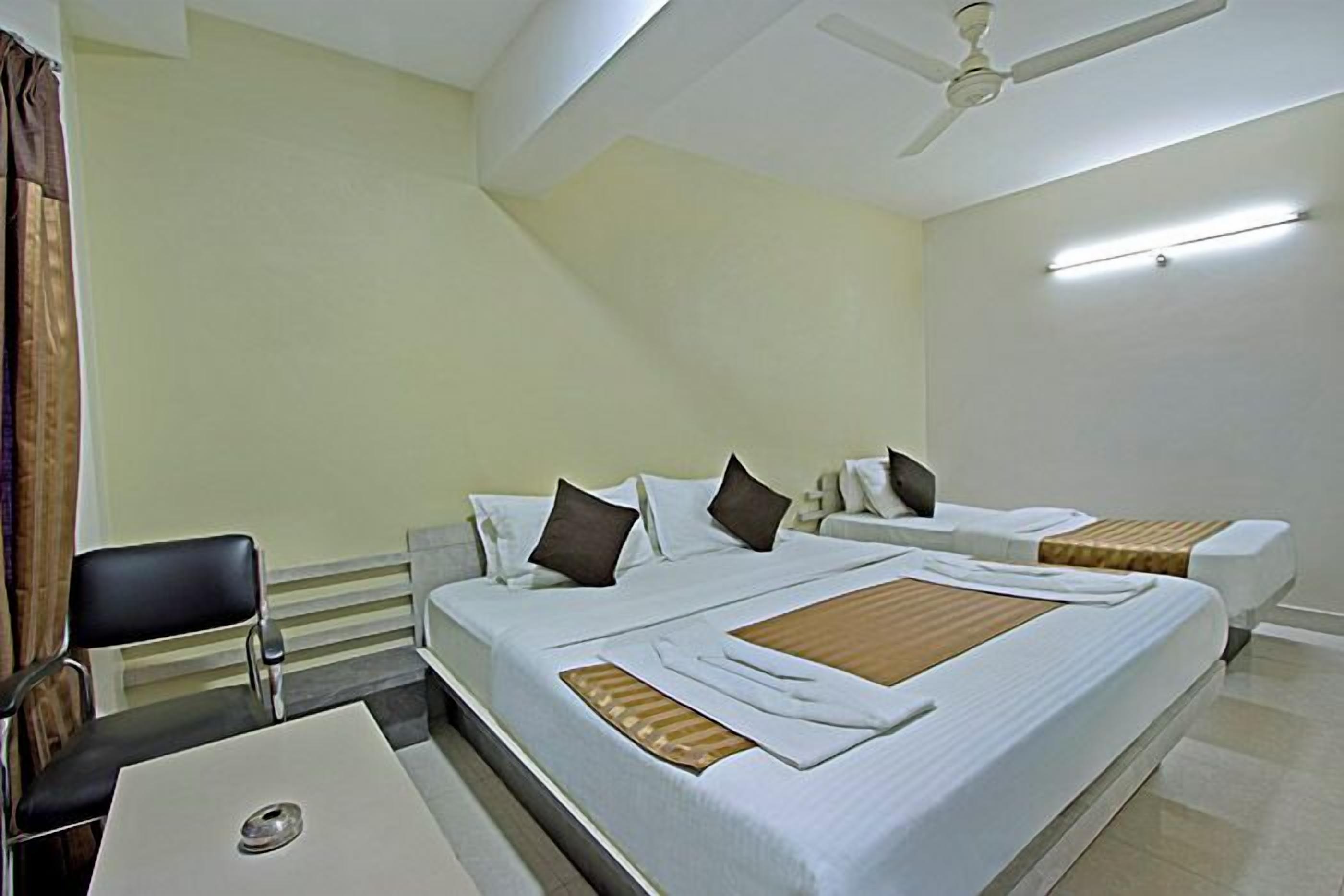 A hotel room with two beds, a desk, and a chair.