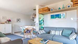 A modern living room with a sofa, coffee table, and a dining area with a chair and table.