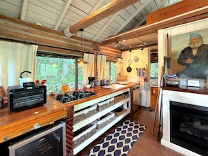 A rustic kitchen with wooden beams, a built-in oven, a coffee station, and a fireplace.