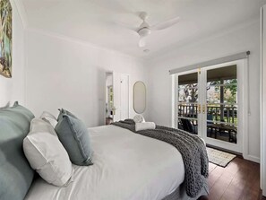 A bedroom with a bed, a ceiling fan, a large window, and a view of the outdoors. - Newberry Cottage: Beach, Games & Alfresco Bliss (Dunsborough)