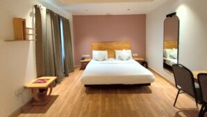 Una habitación de hotel con una cama grande, una mesita de noche, una silla y un espejo.