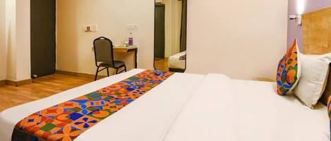 A hotel room with a bed, a desk, a chair, and a mirror.